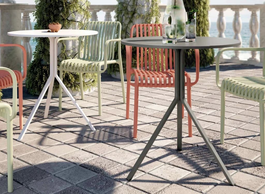 Terraza junto al mar con mesas redondas y sillas de exterior en verde y teja